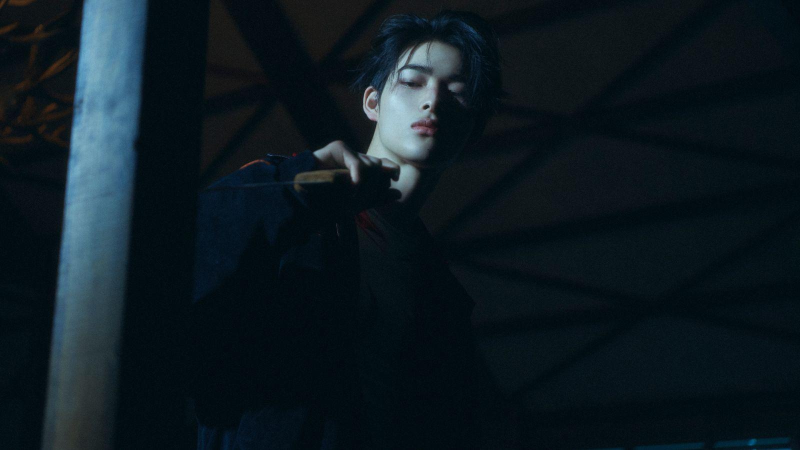 a young man holding a baseball bat in the dark