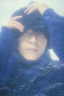 a woman in a blue sweater is covering her face with her hands