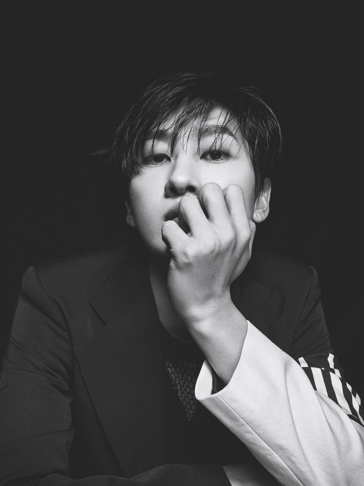 a man in a suit is holding his hand to his mouth