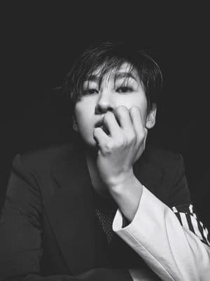 a man in a suit is holding his hand to his mouth