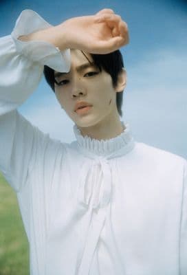 a woman in a white shirt holding her hand up to her head