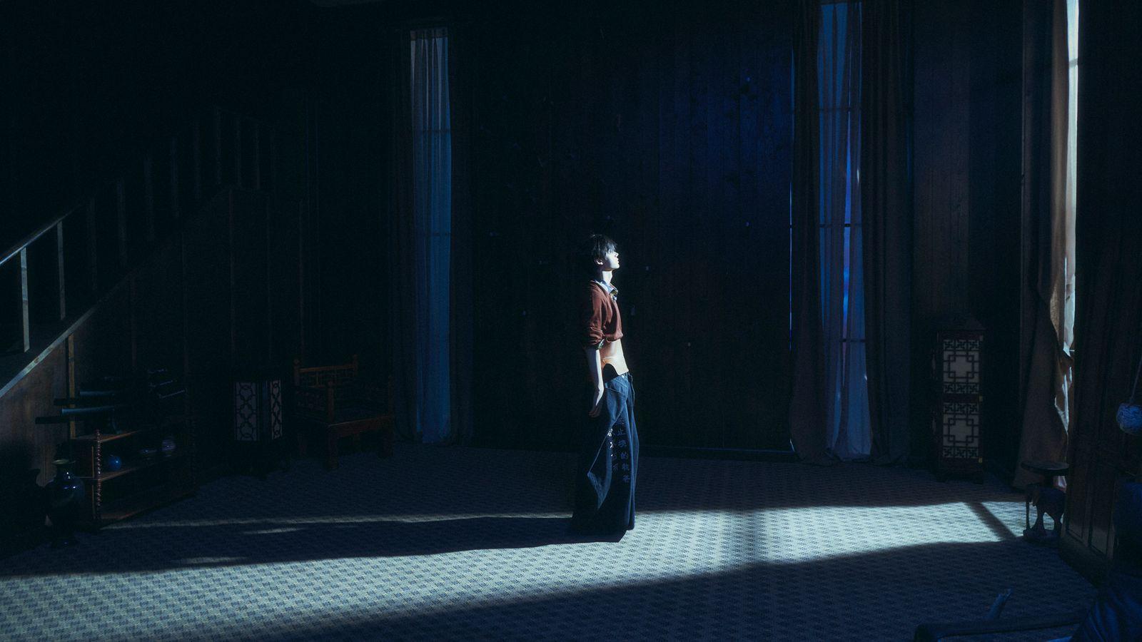 a person standing in a dark room with a suitcase