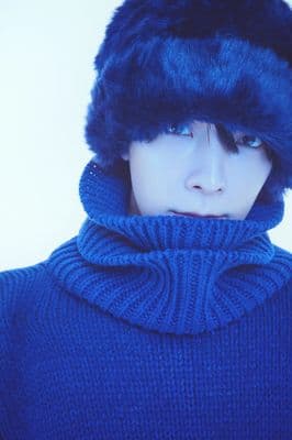 a person wearing a blue sweater and a fur hat
