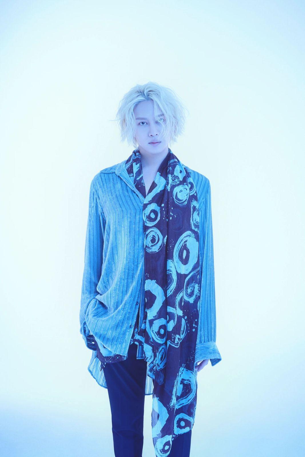 a woman with white hair wearing a blue shirt and black pants