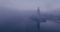 a foggy city with a clock tower in the distance