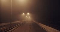 a foggy street with street lights on a foggy night