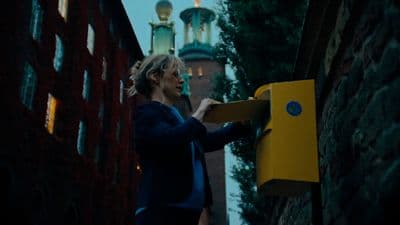 a woman in a blue jacket is holding a yellow box