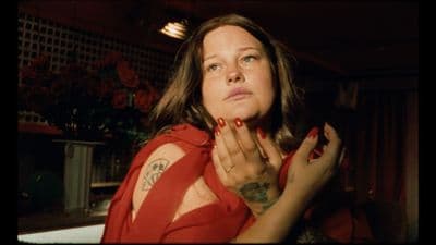 a woman in a red shirt with tattoos on her chest