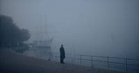 a person standing on a dock in the fog