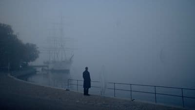 a person standing in front of a boat on a foggy day