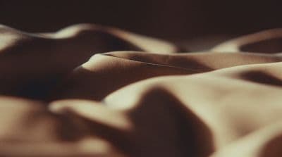 a close up of a bed with a brown comforter