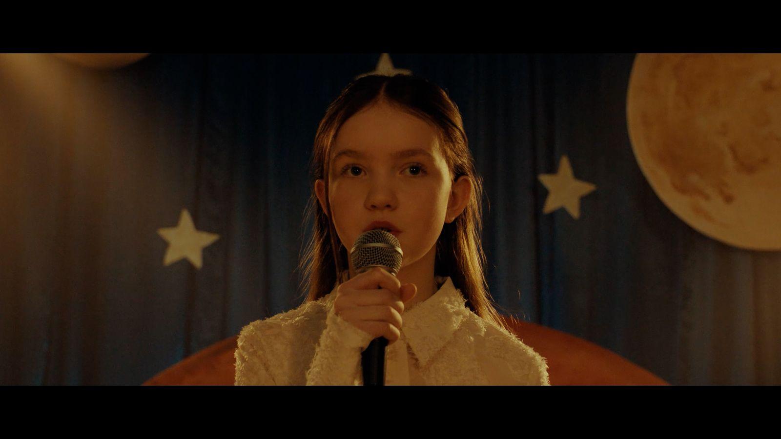 a woman holding a microphone in front of a curtain