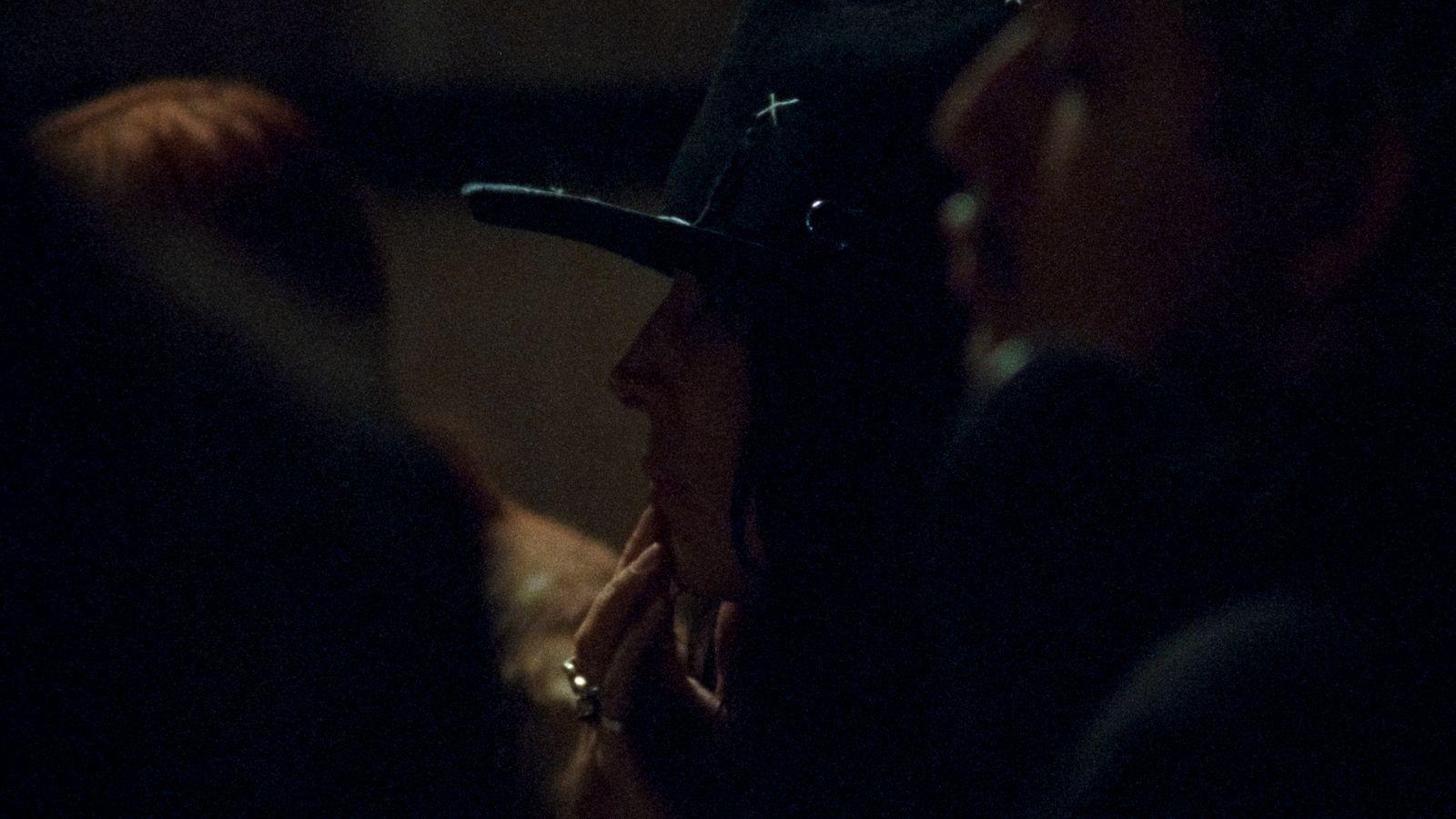 a woman wearing a hat in a dark room