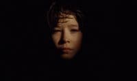 a woman's face in the dark with a black background