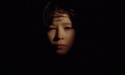 a woman's face in the dark with a black background