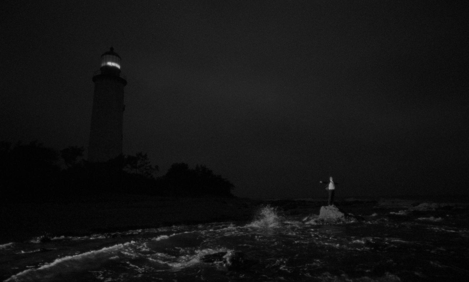 a black and white photo of a lighthouse at night