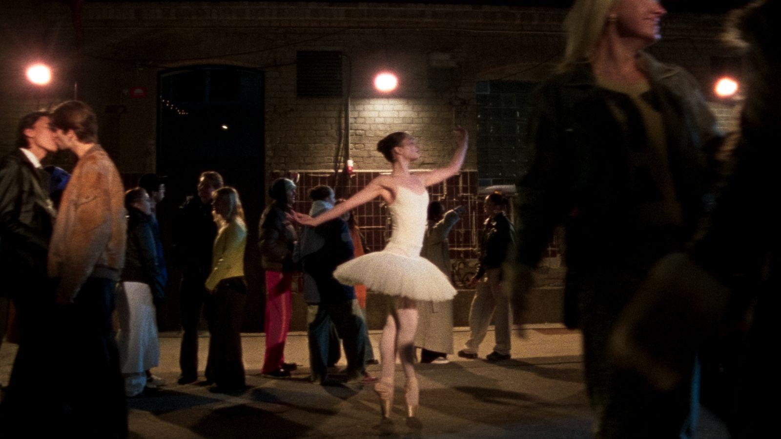 a woman in a white tutu dancing in front of a crowd of people