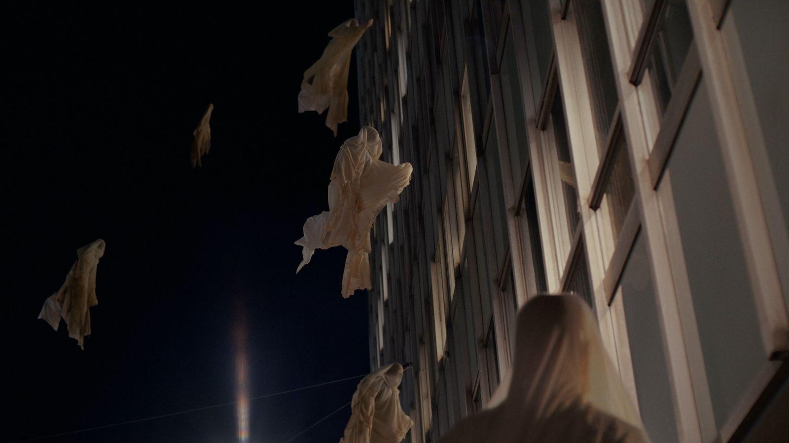 a group of people flying kites next to a tall building