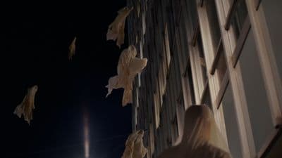 a group of people flying kites next to a tall building