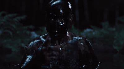 a man in a black body suit standing in the dark
