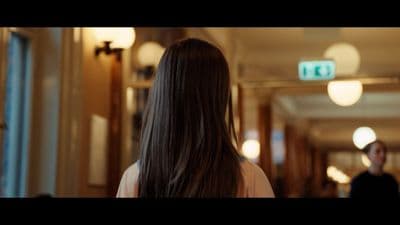 a woman with long hair walking down a hallway