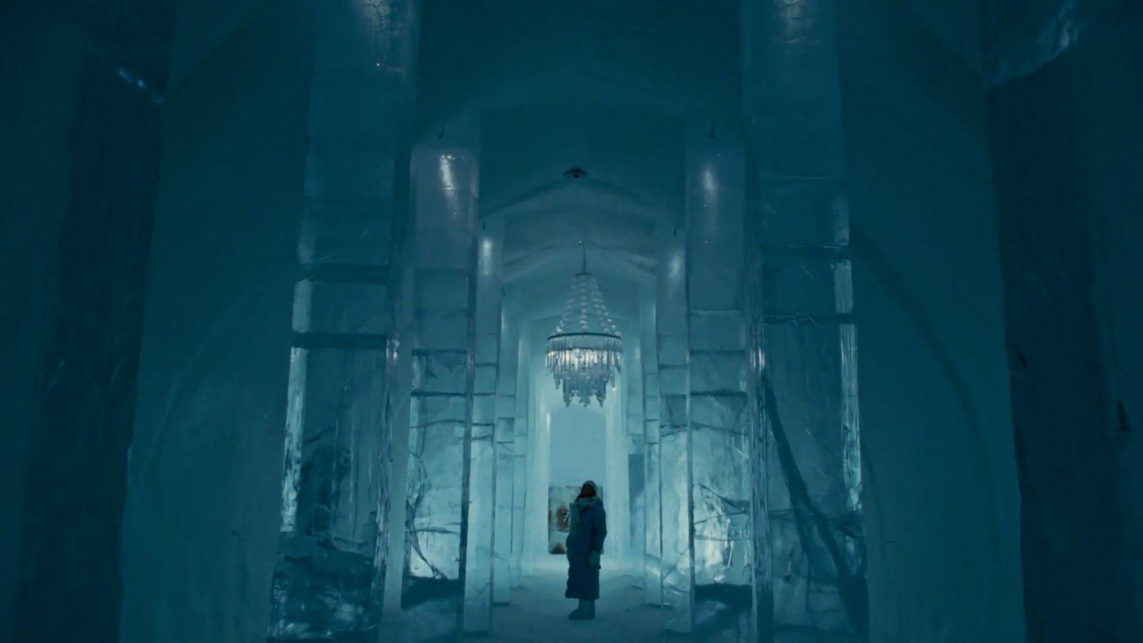 a person standing in an ice tunnel with a chandelier hanging from the ceiling
