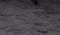 a black and white photo of a man standing on a rocky hill