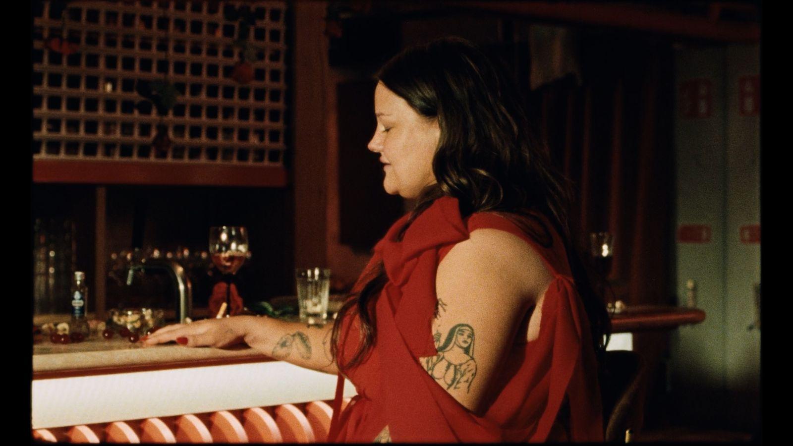 a woman in a red dress sitting at a bar