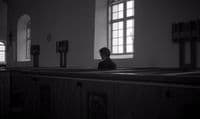 a person sitting in a church looking out the window