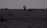 a man running across a field in the middle of the day