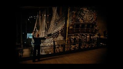 a man standing in front of a painting of a ship