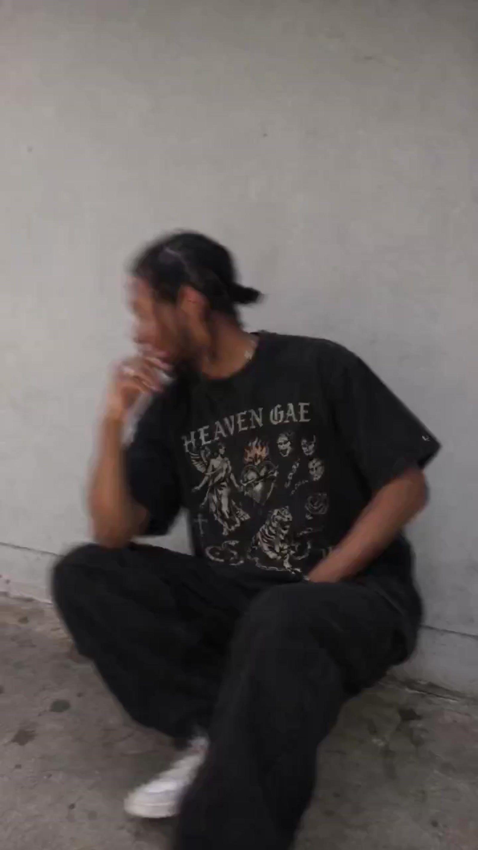 a man sitting on the ground smoking a cigarette