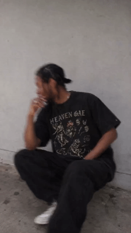 a man sitting on the ground smoking a cigarette