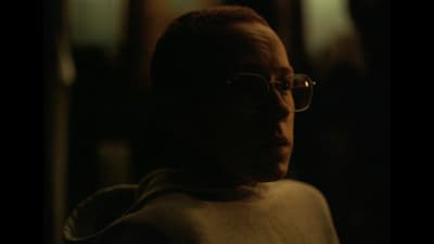  a man wearing glasses in a dark room