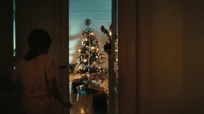 a woman standing in front of a christmas tree