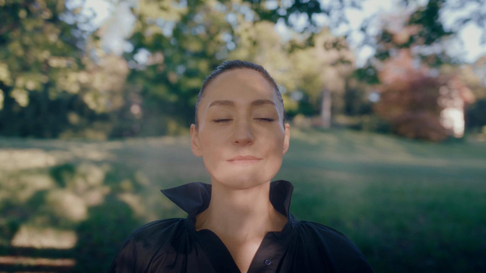 a woman with her eyes closed in a park