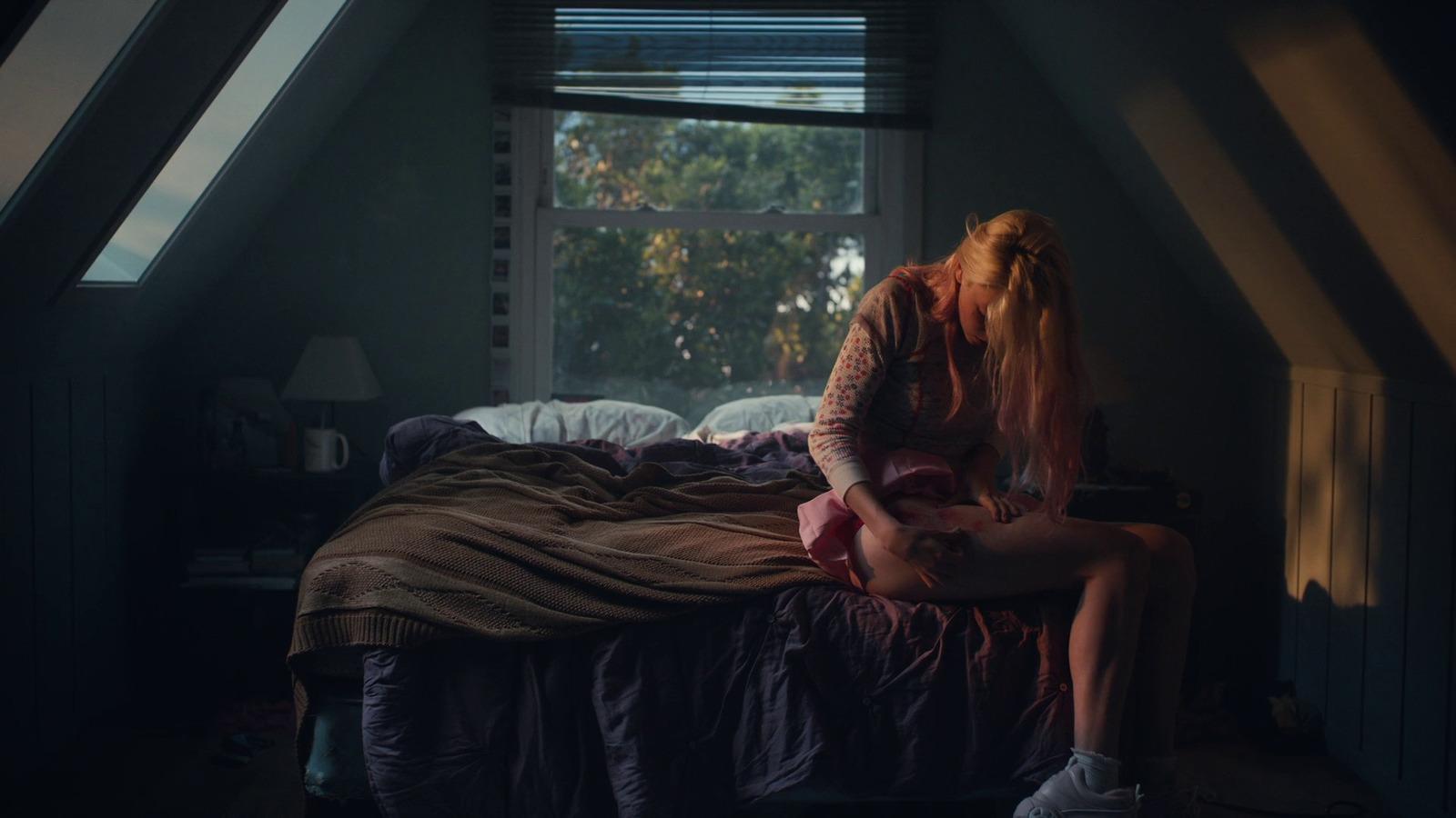 a woman sitting on top of a bed next to a window