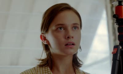 a young girl with a camera in front of a window