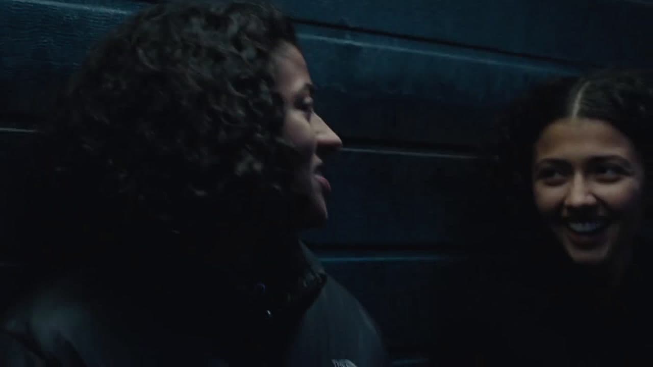  two people standing next to each other in front of a wall