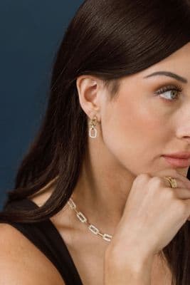 a woman wearing a necklace and a pair of earrings