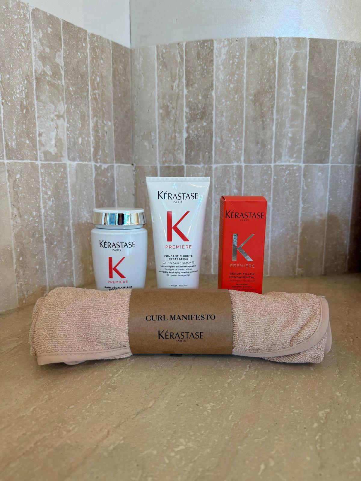 a bathroom counter with a towel, lotion, and a tube of keras