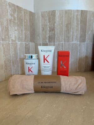 a bathroom counter with a towel, lotion, and a tube of keras