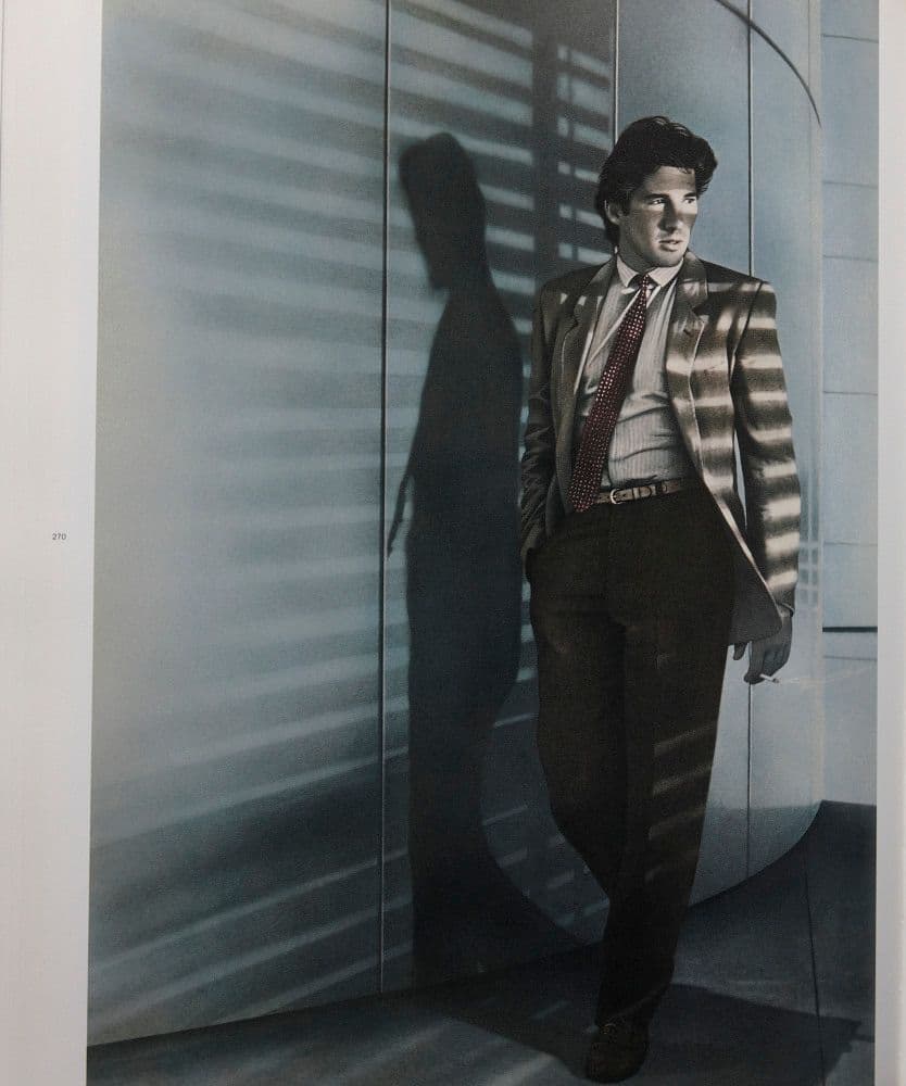 a man in a suit and tie standing in front of a wall