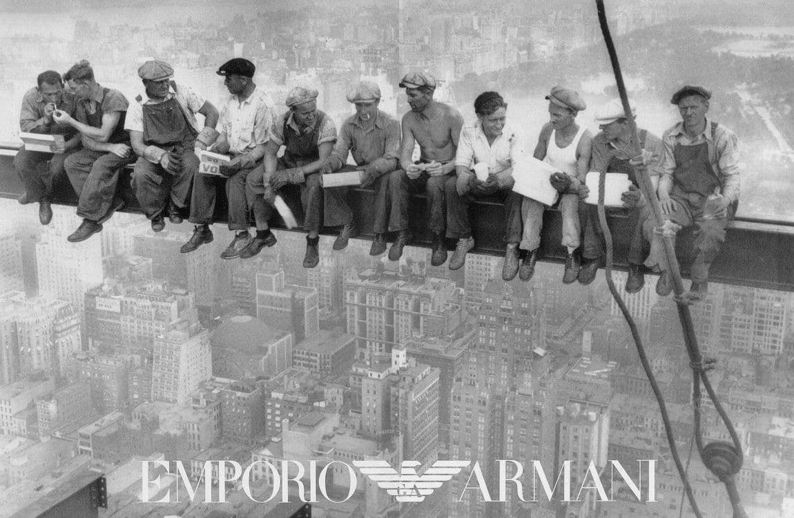 a group of men sitting on top of a tall building