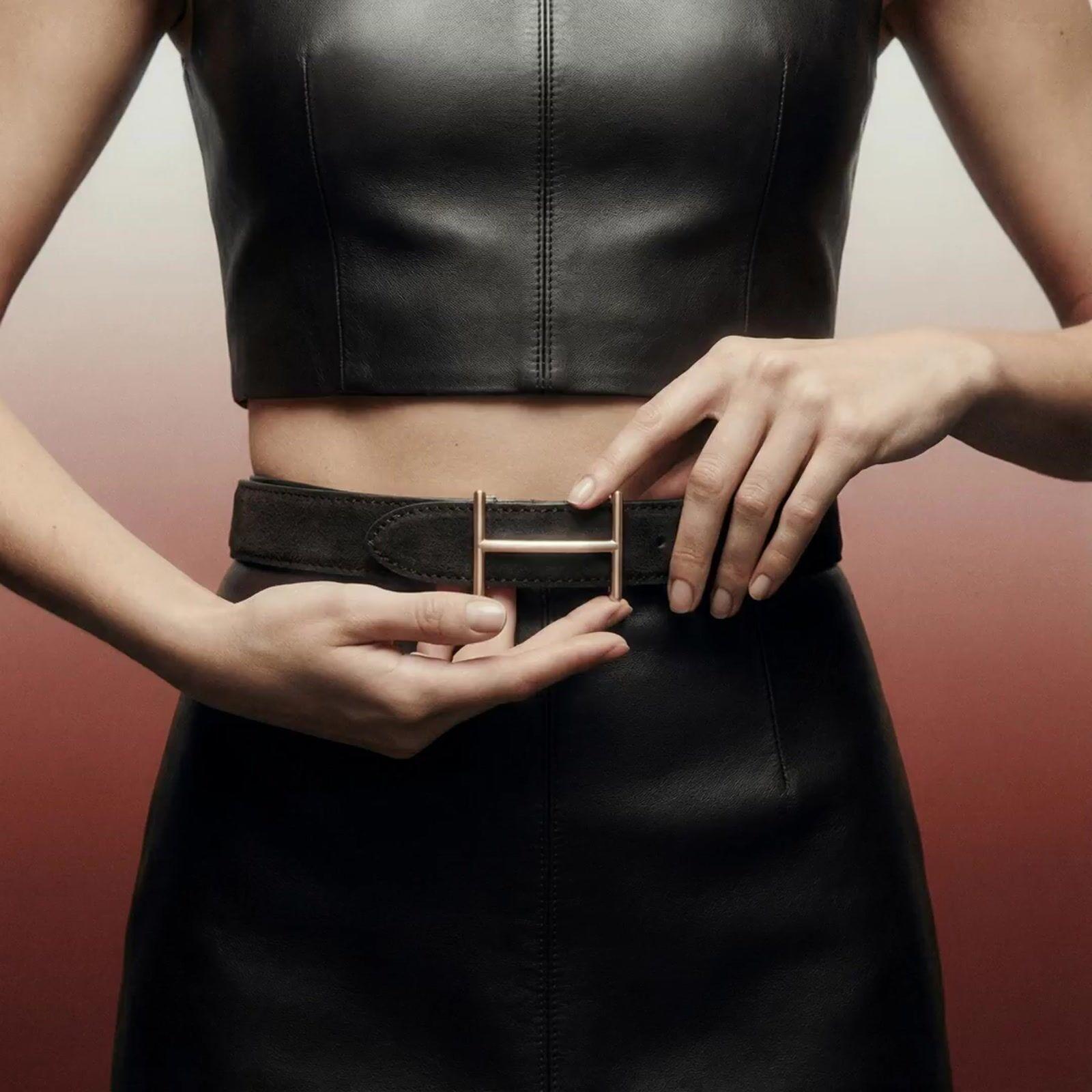 a woman wearing a black leather dress and a belt