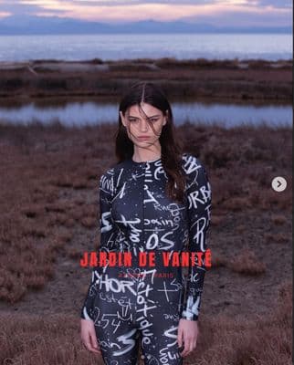 a woman standing in a field next to a body of water