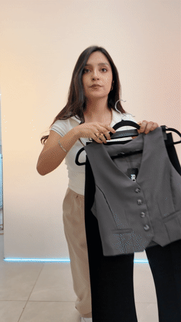 a woman holding up a gray suit jacket