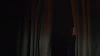 a woman standing in front of a curtain in the dark