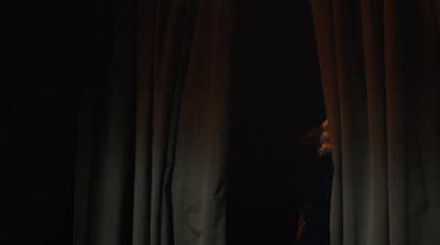 a woman standing in front of a curtain in the dark
