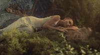 a woman laying on a rock in a forest
